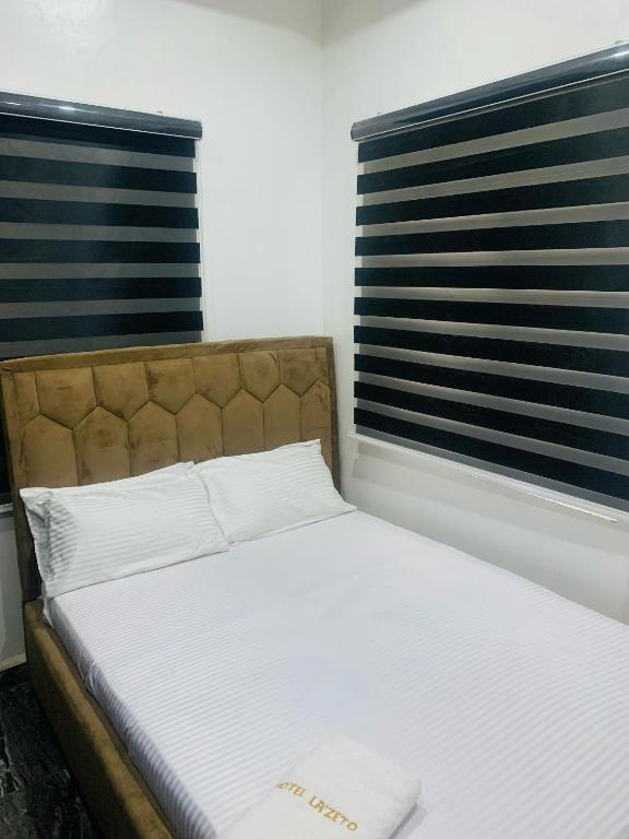 a bed in a room with two windows at Lazeto Hotel & Resort in Zokoja