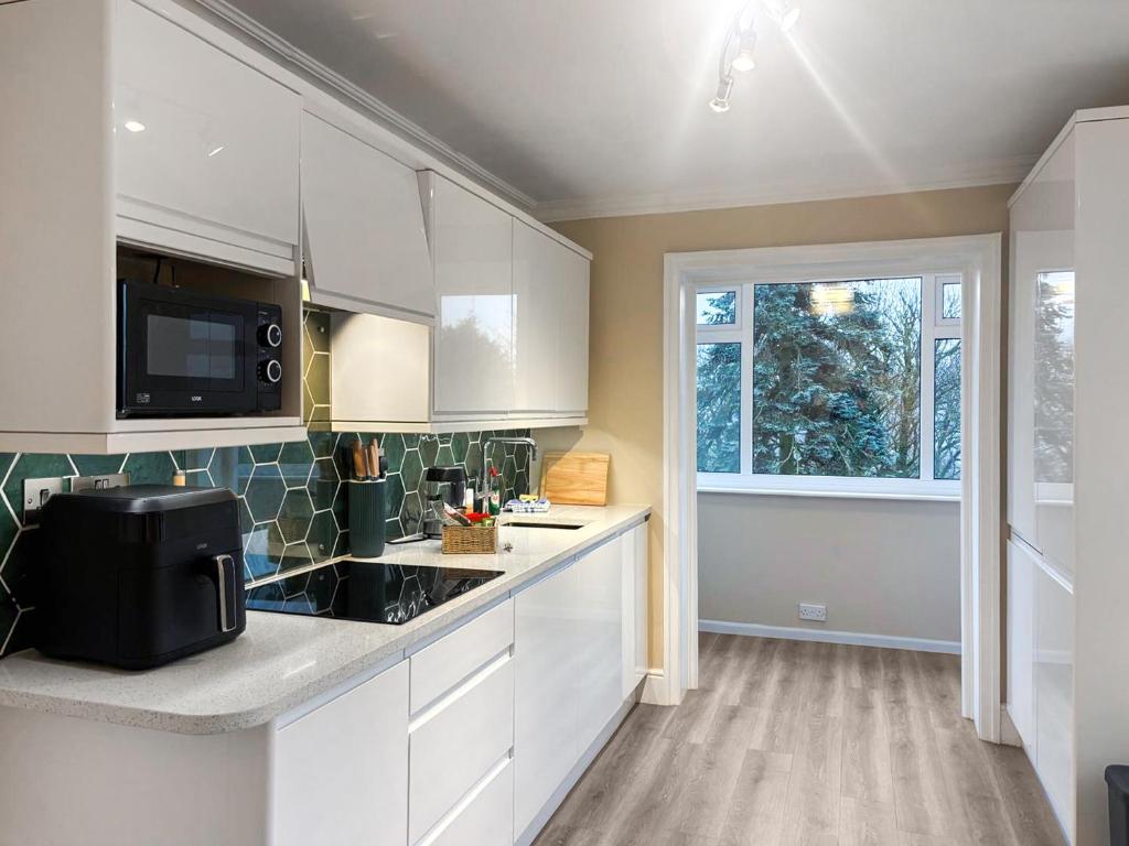 a kitchen with white cabinets and a window at Treetops in Baildon