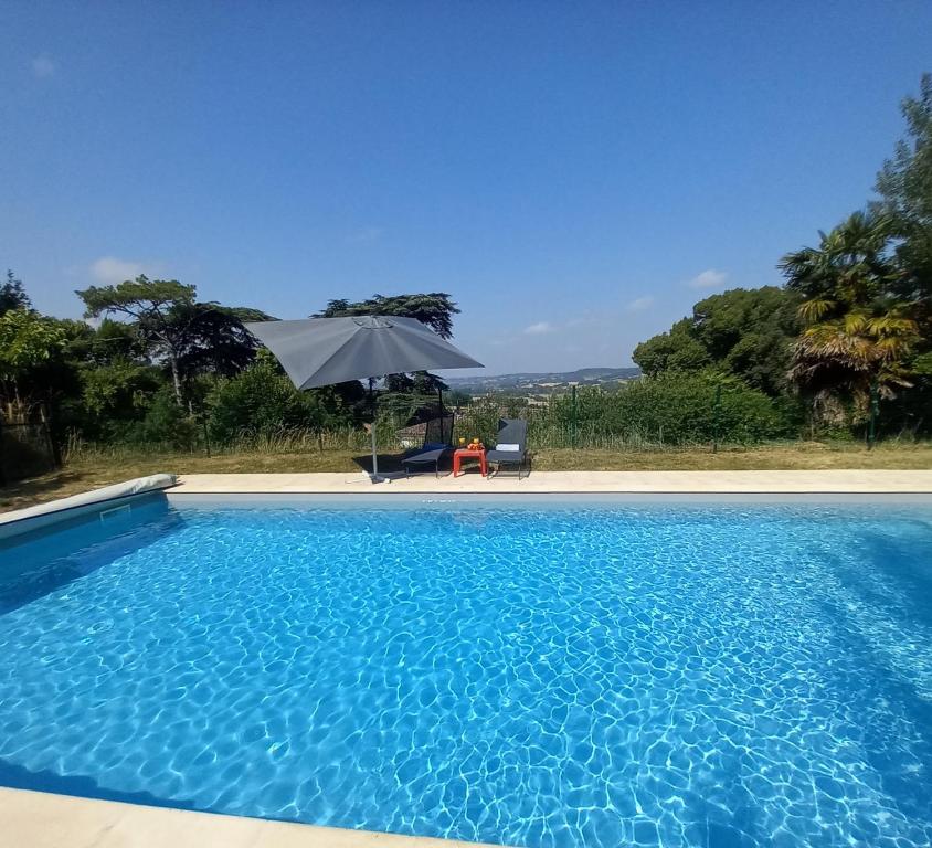 a swimming pool with an umbrella and a table and chair at Domaine La Salamandre - Piscine & Forêt privée, Vue sur Vallée in Lauzerte