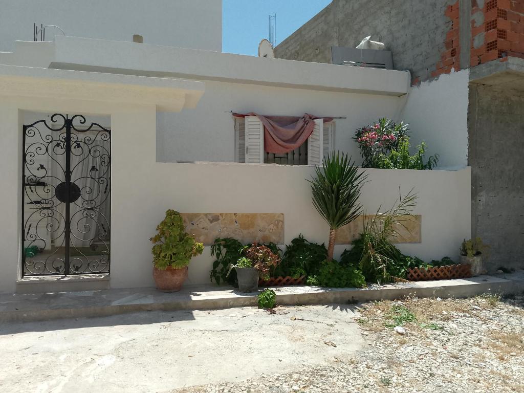 a white house with a gate and plants at Darna in Raʼs al Jabal