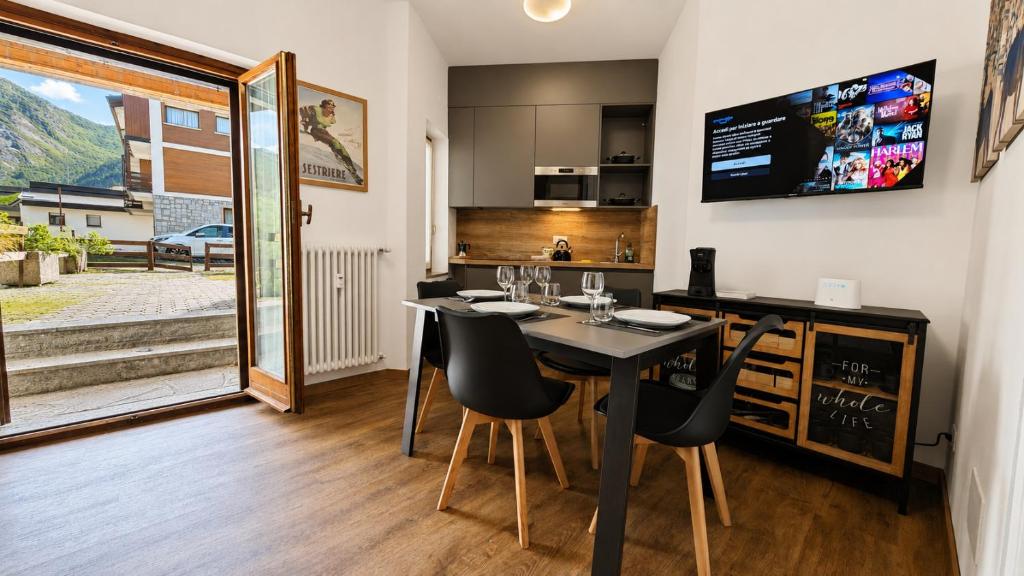a dining room with a table and chairs and a kitchen at Hostdomus - Royal Oak in Sestriere