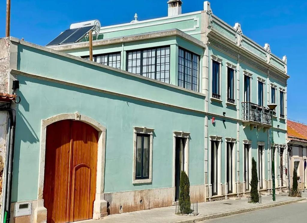 a blue building with a wooden door on a street at Casa D'avó Souzinha in Ermidas