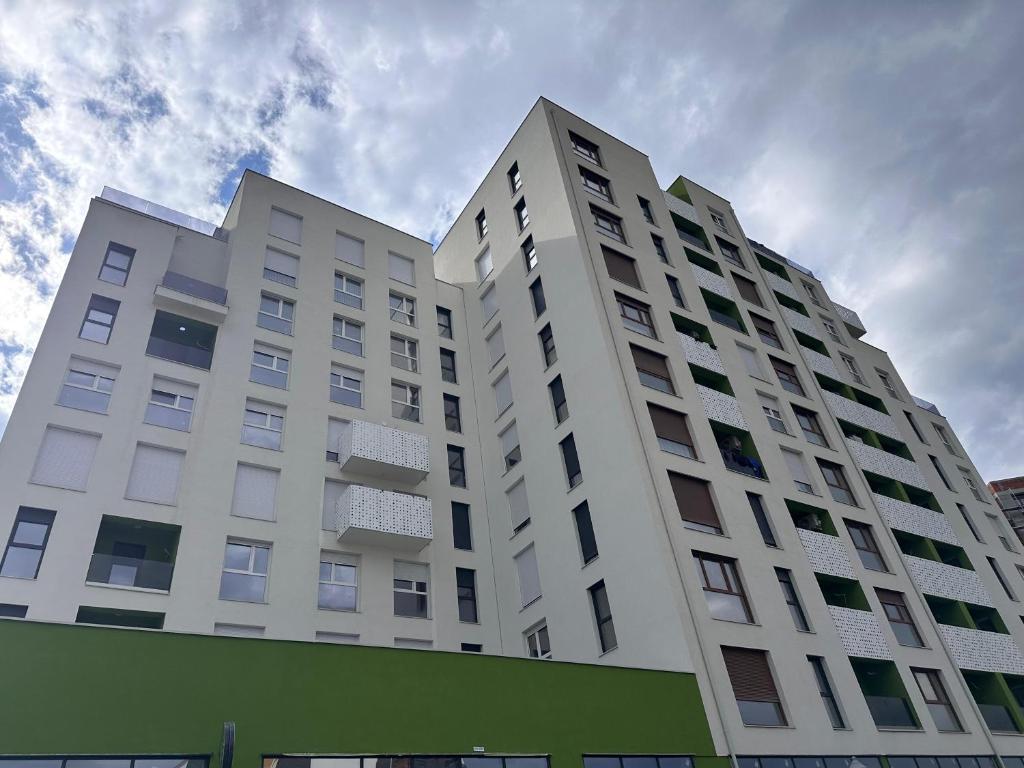 a tall white building with a sky in the background at Pines Apartment in Kosovo Polje
