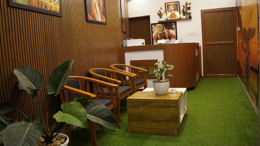 a waiting room with green carpet and chairs and plants at Roys Rooms in Kumarakom