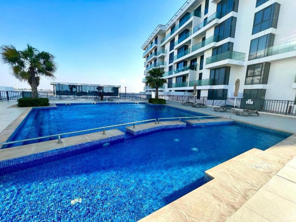 a large blue swimming pool next to a building at Ajmal Makan City in Sharjah