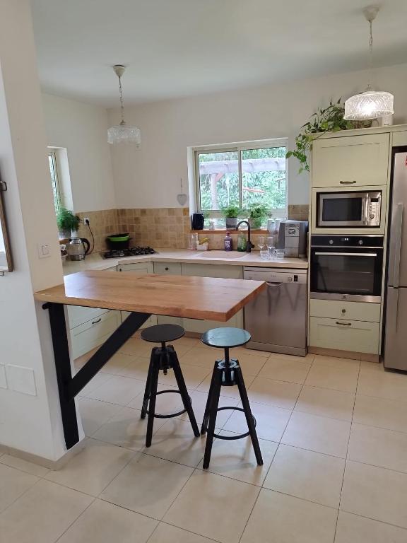 a kitchen with a wooden table and two bar stools at SnirBen zvi in Kibbutz Snir