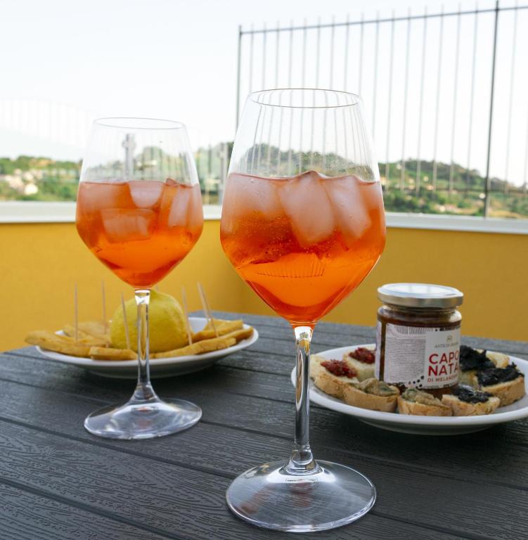 two wine glasses sitting on a wooden table with food at La Dimora Di Segesta in Calatafimi
