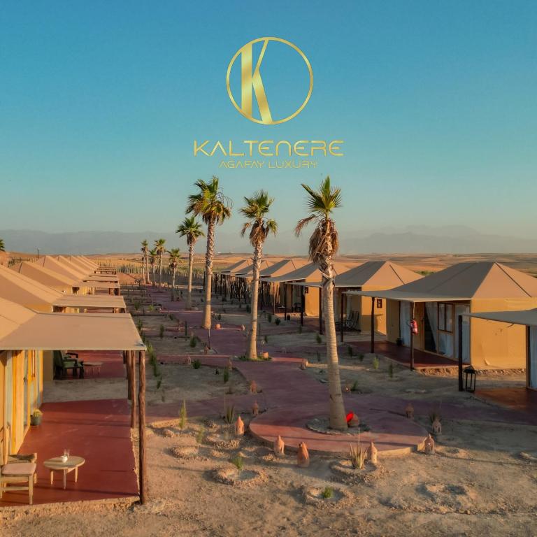 a group of palm trees and buildings in the desert at Kal Tenere Luxury Camp in El Karia