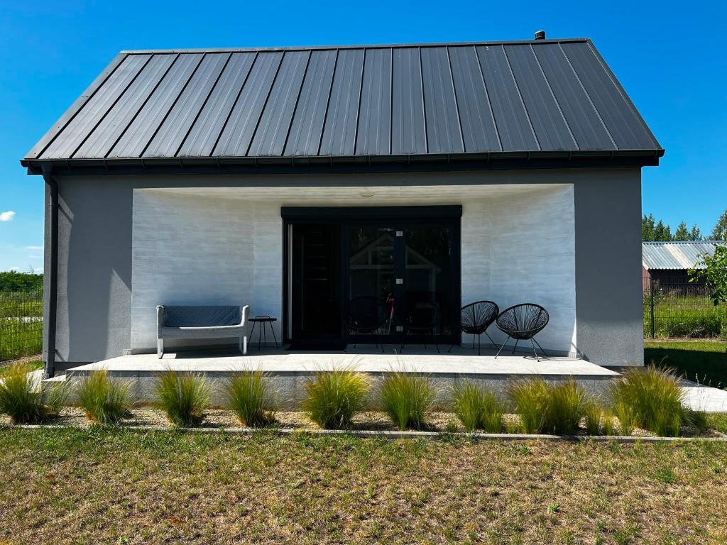 a white building with a black roof and a couch at Domki za Wyspą in Chmielów