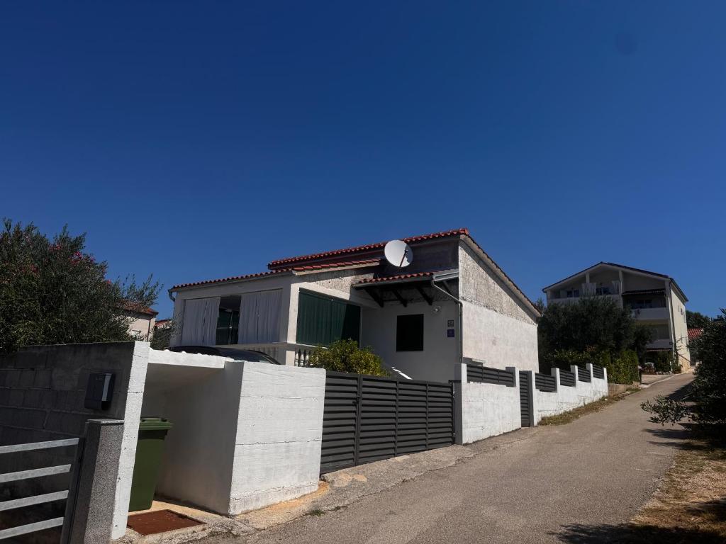 a white house with a fence in front of it at Holiday Home Mirta in Pakoštane