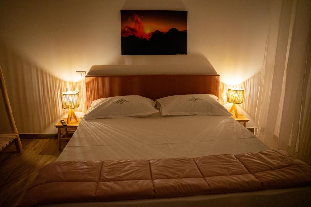 a bedroom with a large white bed with two lamps at 99 Rooms in LʼAquila