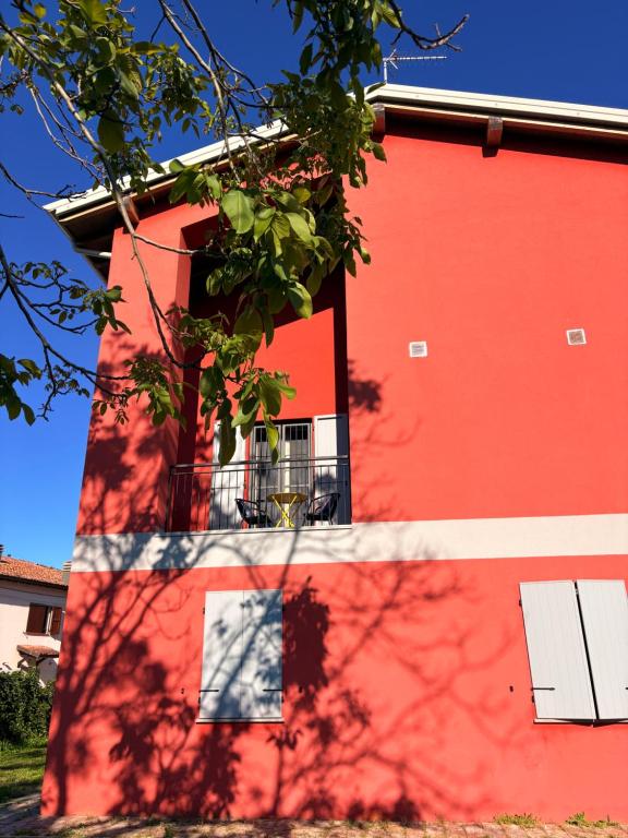 a red building with a tree in front of it at Sala dell Estate Guest House in Secchia