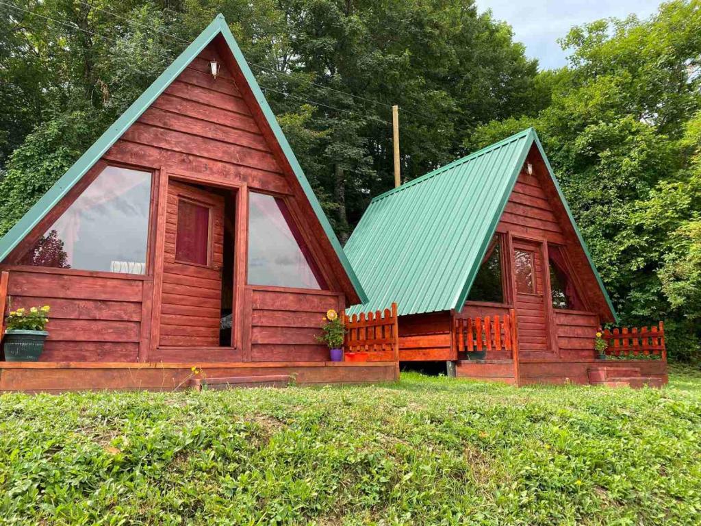 a red cabin with a green roof on a field at Etno selo -ŠAPAT- in Šavnik
