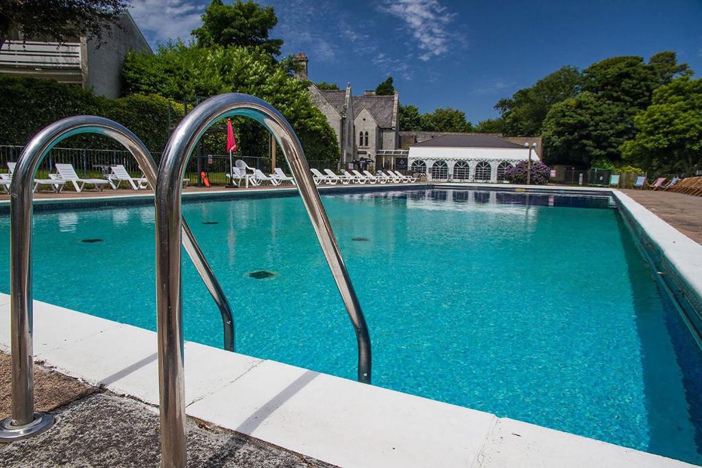 a swimming pool with blue water and metal rails at Newquay Coast and Cabin in Saint Columb Road Station