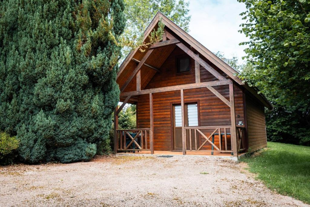 a wooden cabin with a large tree at Domaine Guillaume Chalet 6p classic in Auquainville