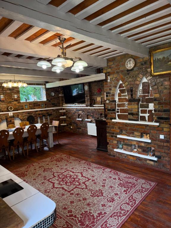 a dining room with a table and a brick wall at Loukis dvars in Luokė