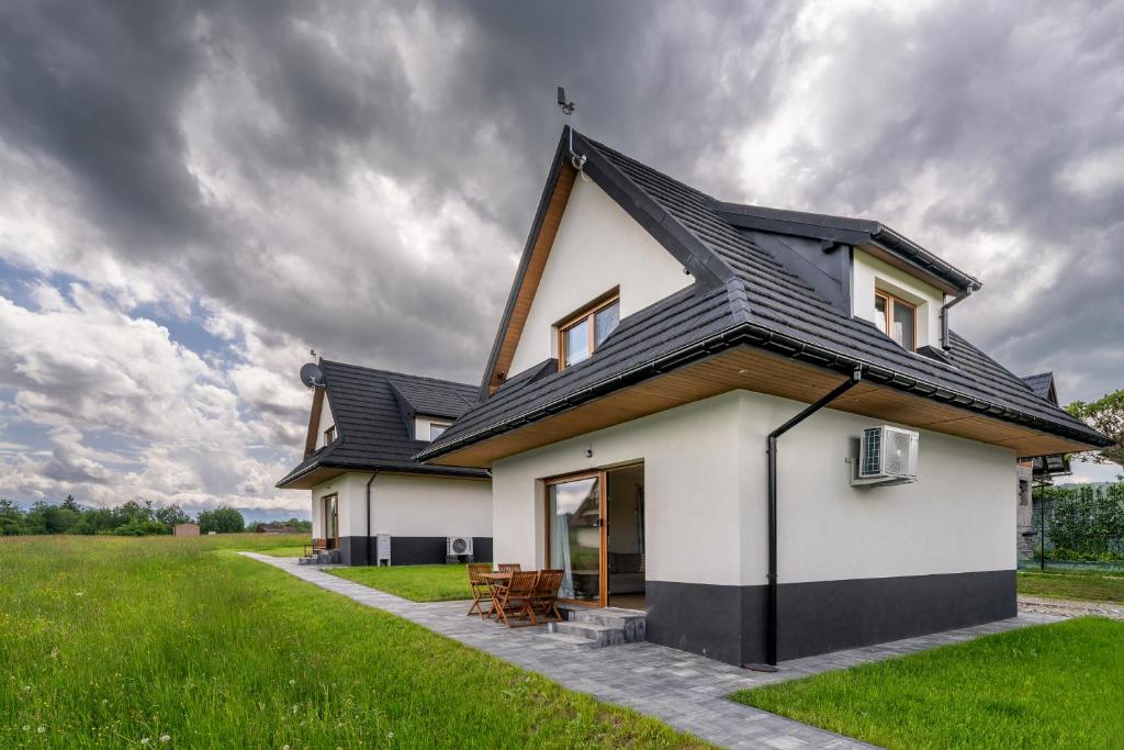 a house with a black roof and a green field at Czarna Owca in Biały Dunajec