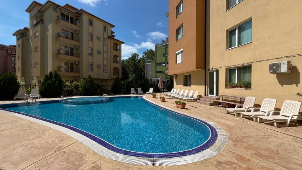a swimming pool in a courtyard with chairs and buildings at AMADEUS I Studio 25 Sunny Beach in Sunny Beach
