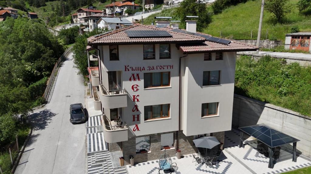 a building with a sign on the side of it at Къща за гости Мекана in Borino