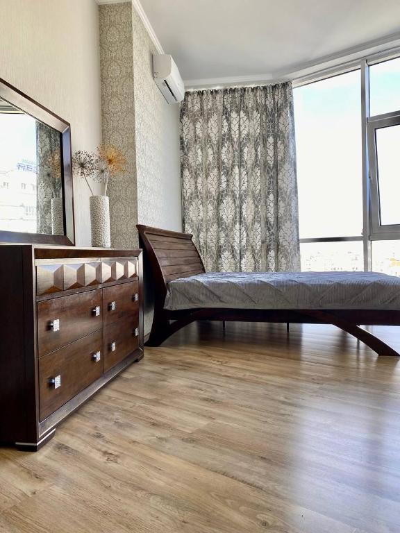 a bedroom with a bed and a dresser and a large window at Марсельская Residence in Kryzhanivka