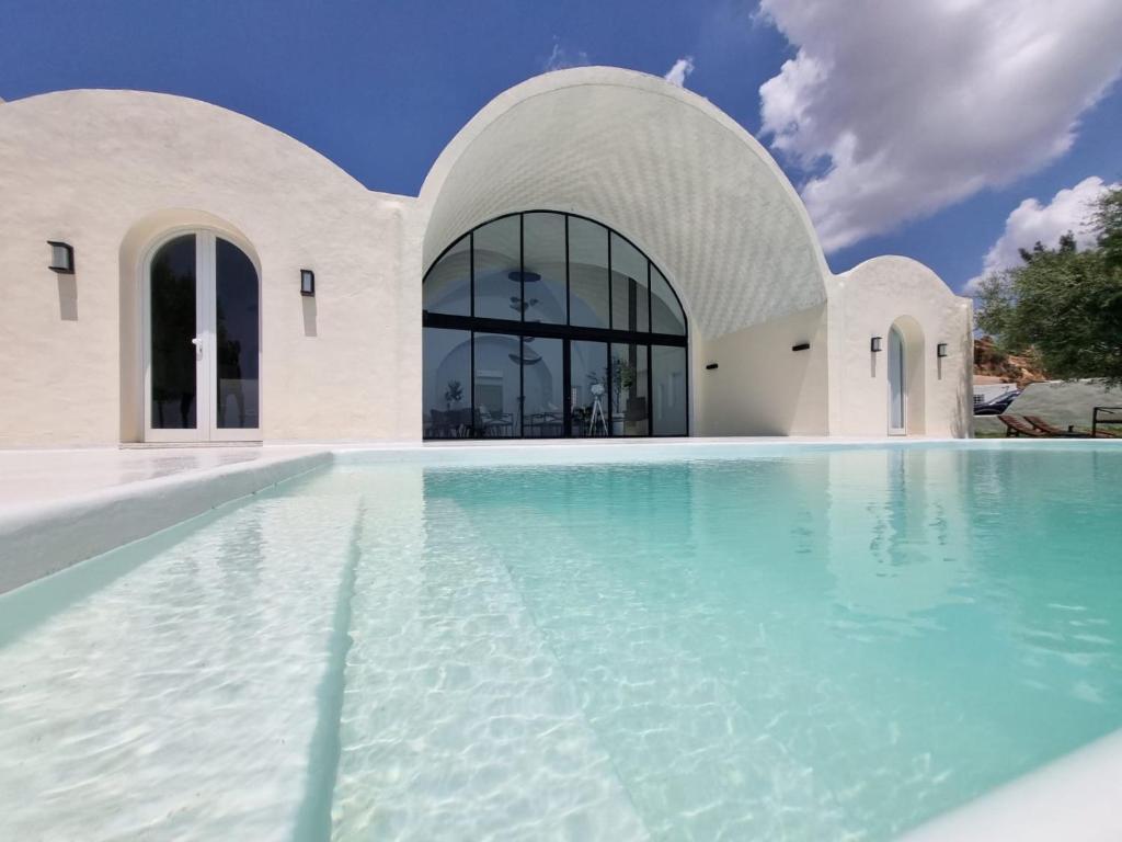 a swimming pool with blue water in front of a building at Dar El Monchar - Hammamet in Hammamet