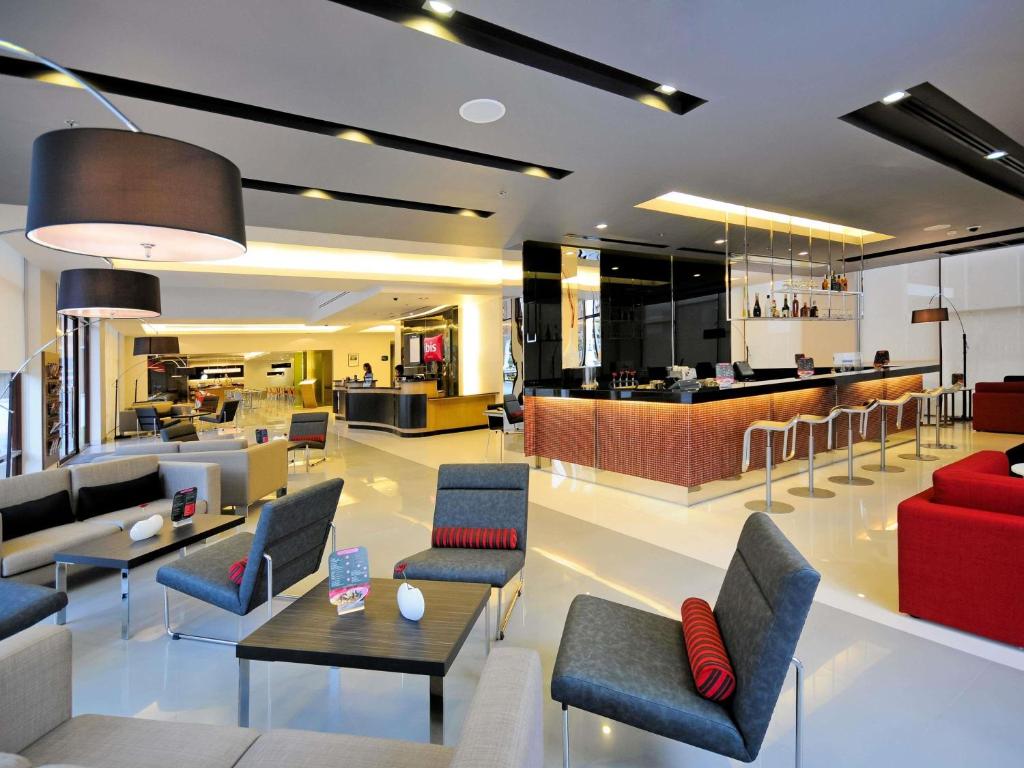 a lobby with chairs and tables and a bar at Ibis Bangkok Sukhumvit 4 in Bangkok