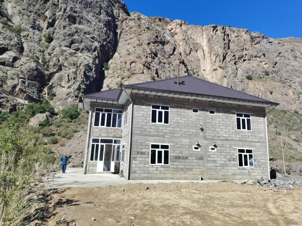 a building in front of a rocky mountain at Nofin Lake House in Panjakent