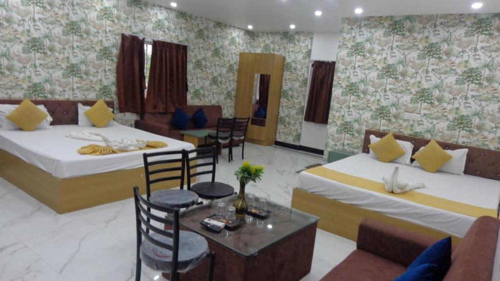 a hotel room with two beds and a table and chairs at Hotel Rudra Heritage in Jasidih