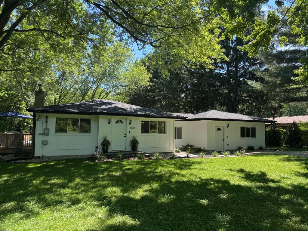 a small white house in a yard with trees at The Borderland in Michigan City