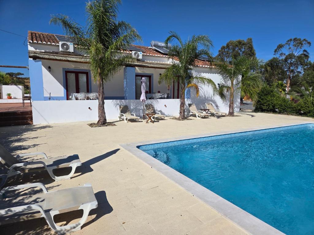 a house with a swimming pool and palm trees at Monte da Calcadinha in Ourique