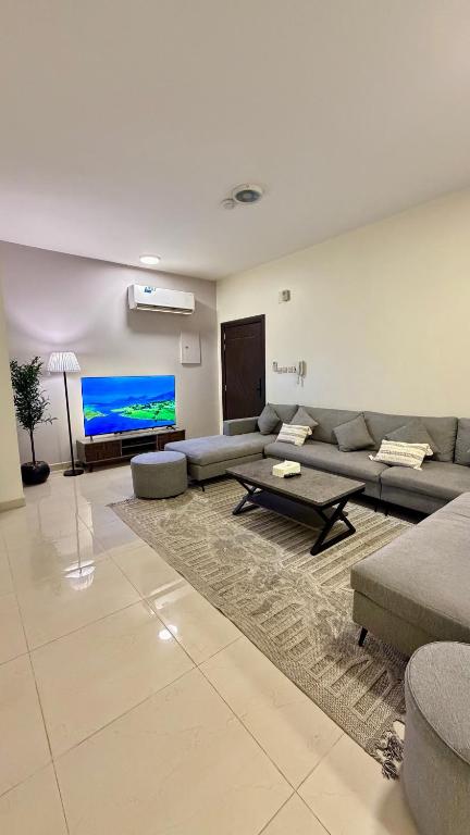 a living room with a couch and a large screen tv at اكنان للشقق المفروشة in Buraydah