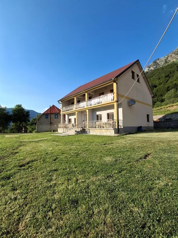a large building with a grass field in front of it at Guest House Trojani in Lëpushë