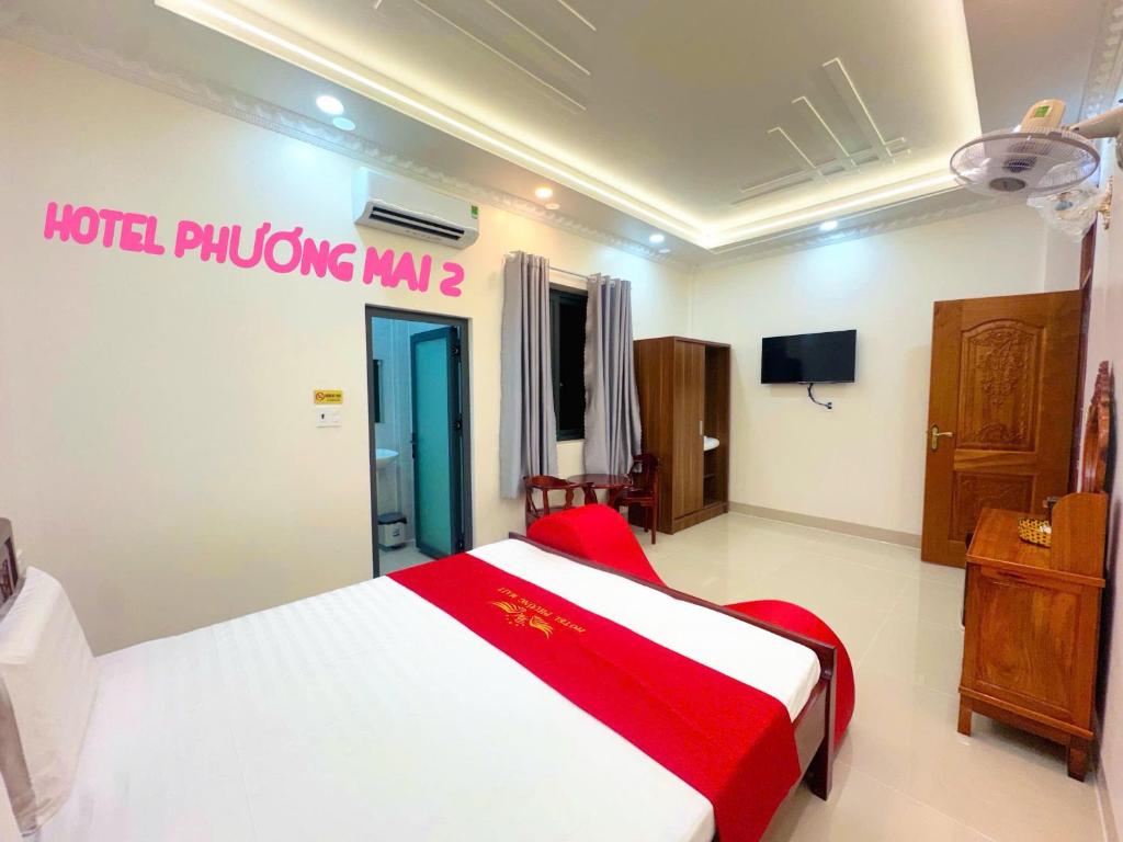 a bedroom with a red and white bed and a television at Hotel PHƯƠNG MAI 2 in Bến Lức
