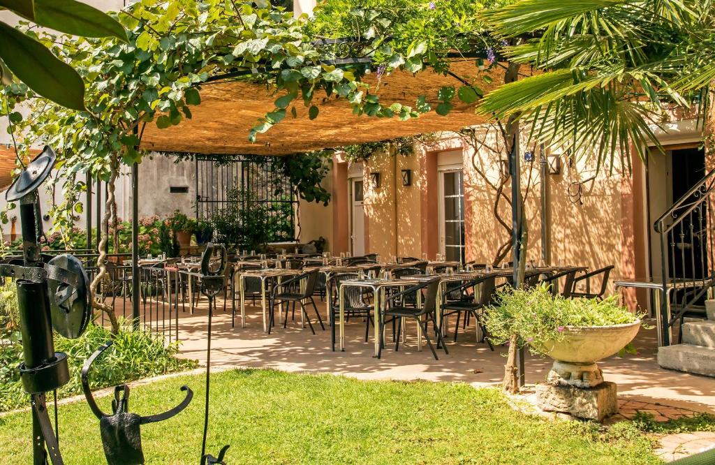 patio ze stołami i krzesłami pod pergolą w obiekcie Hôtel Restaurant Les Touristes w mieście Vals-les-Bains
