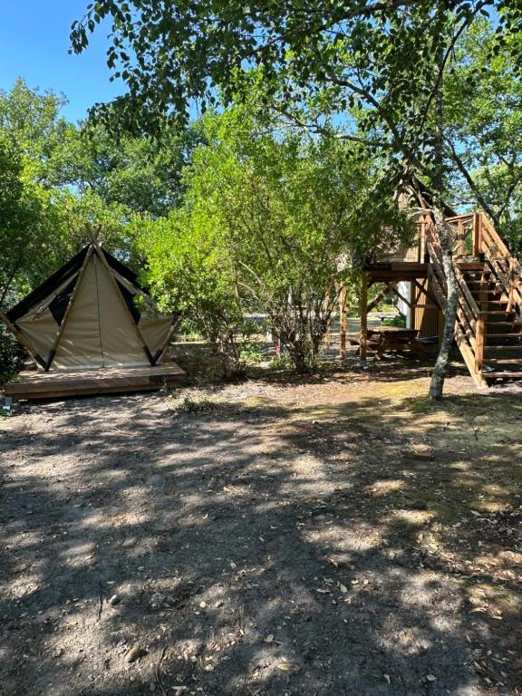 a tent and a wooden structure next to some trees at Camping Le Capdeville in Carcans