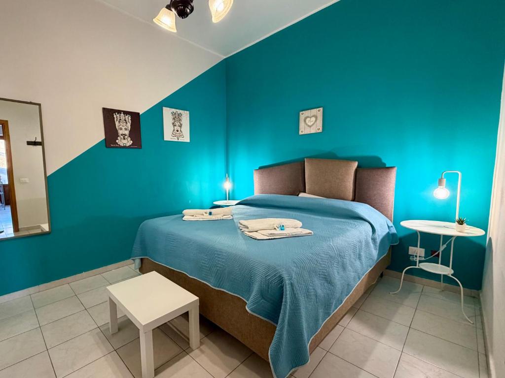 a blue bedroom with a bed and a table at TESEO Siracusa in Ortigia fuori dalla ZTL in Syracuse