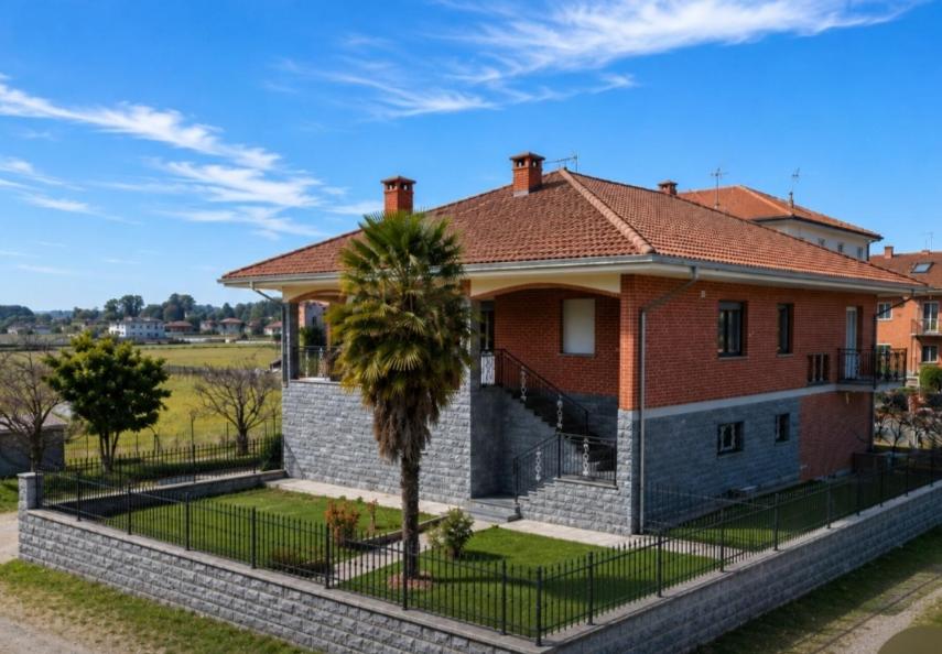 a house with a palm tree in front of a fence at Villa Marie in Alpignano