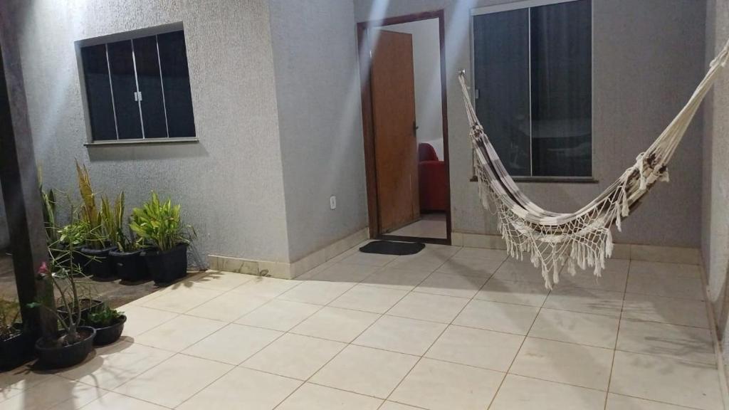 a hanging hammock in a room with potted plants at Casa com varanda, garagem e cozinha completa in Formosa