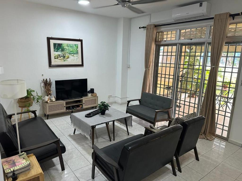 a living room with black chairs and a tv at Casa Sara in Nilai