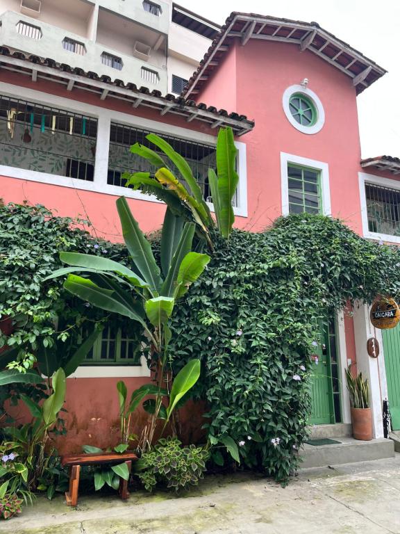 a pink house with a plant in front of it at Caiçara Guest House in Ubatuba