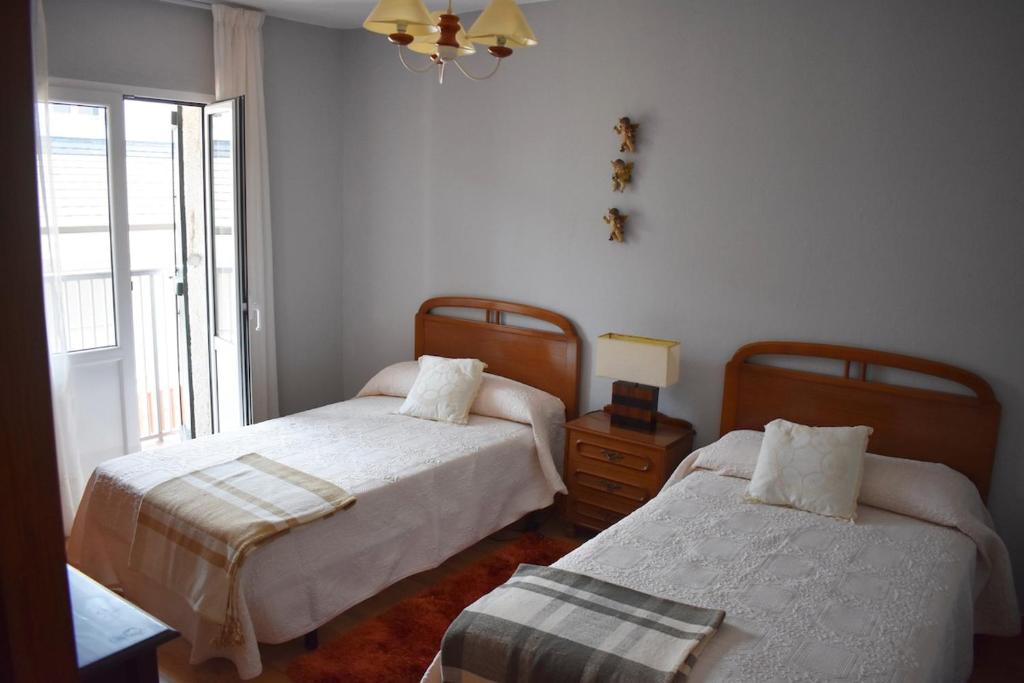 a bedroom with two beds and a window at Casa Nicolás in Portomarin