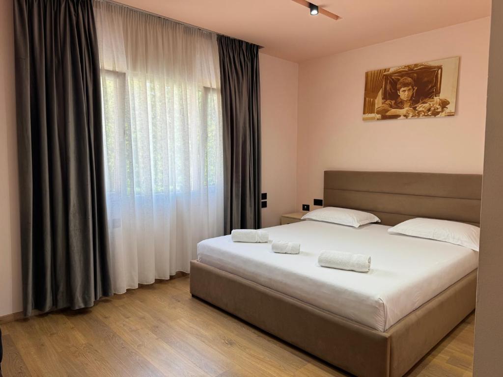 a bedroom with a large bed and a large window at Hotel Djakbe in Tirana