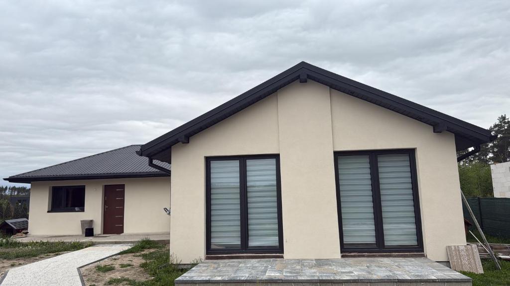 una piccola casa bianca con il tetto nero di Chill and Grill - Modlin Airport Apartamenty na wynajem a Wola Smolana