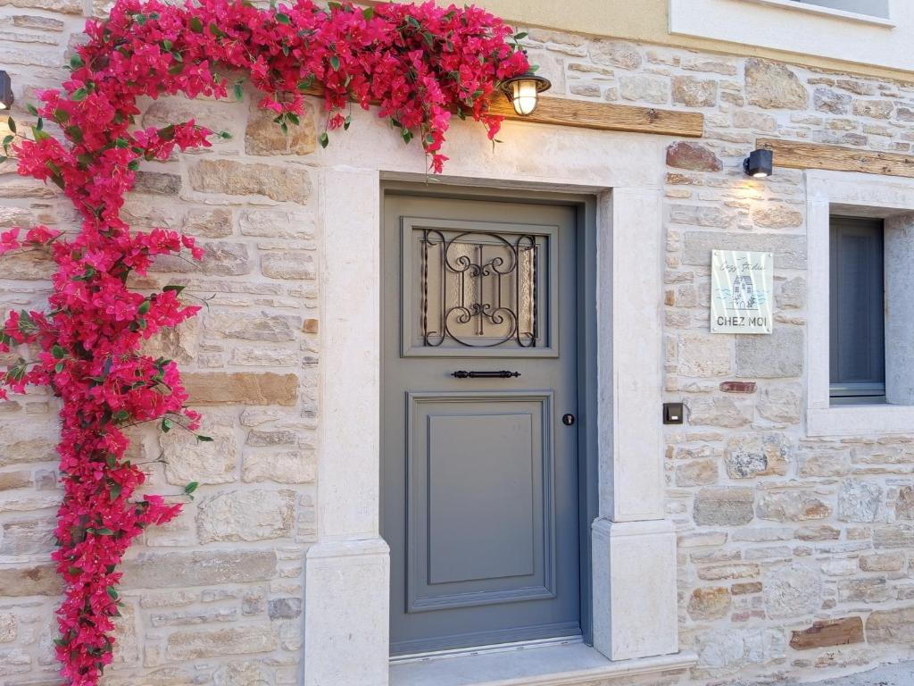 a gray door on a stone building with red flowers at cozystudio Chezmoi in Chios