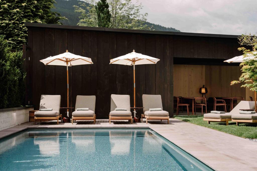 a group of chairs and umbrellas next to a pool at Arx Boutiquehotel in Schladming