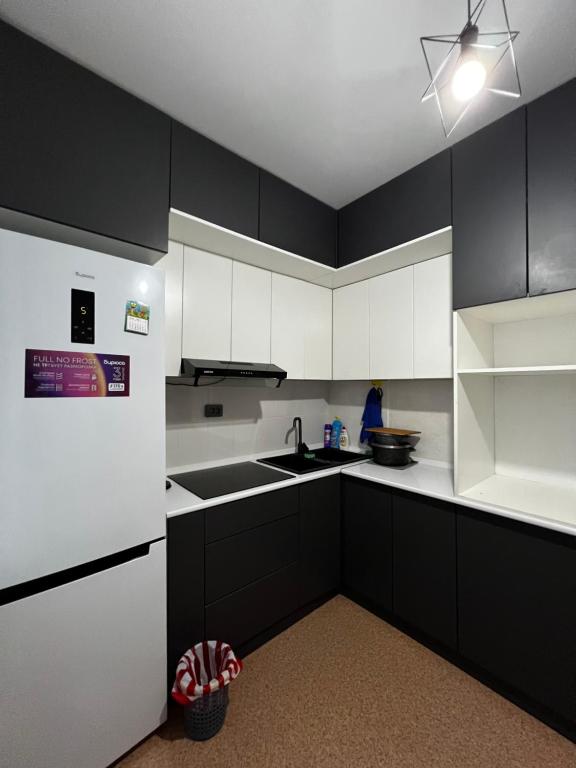 a kitchen with black cabinets and white appliances at Квартира in Balqash