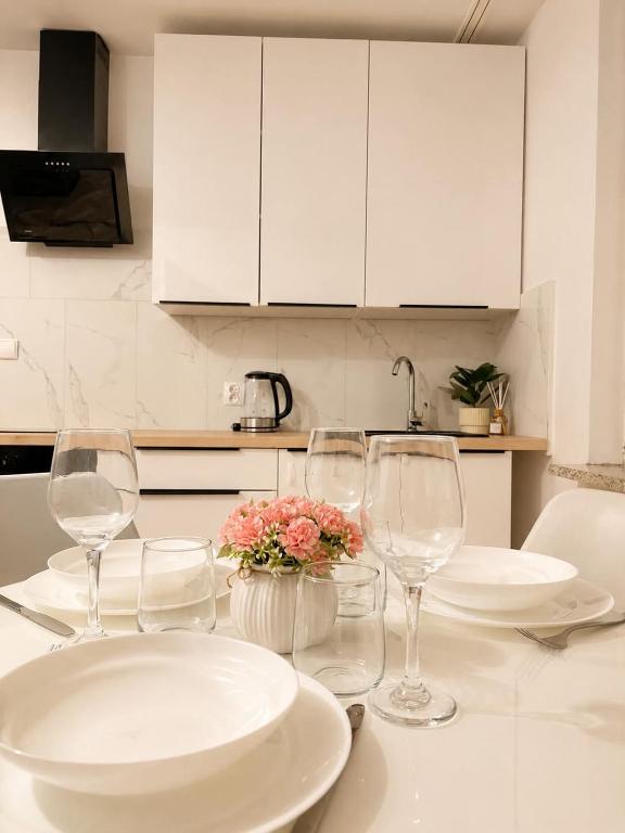 a table with glasses and plates and flowers on it at Apartament 3 Maja in Brodnica