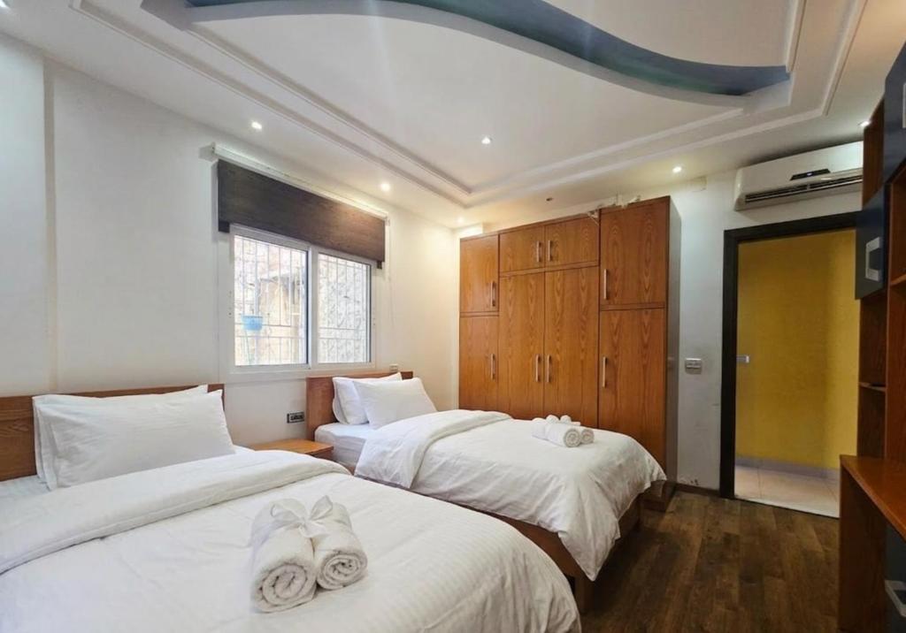 a bedroom with two beds with white sheets and a window at New Halat, Linda in Jbeil