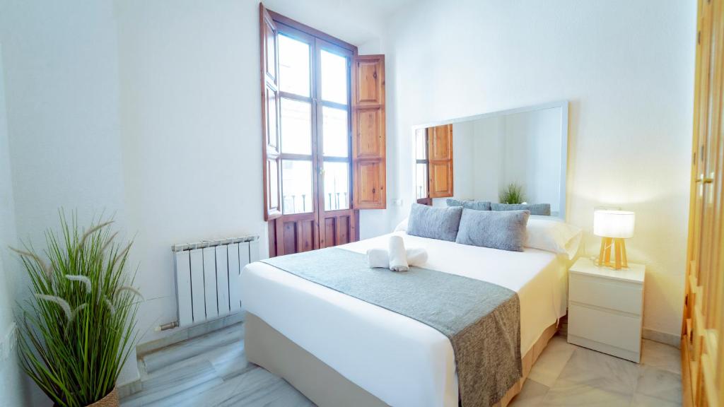 a bedroom with a white bed and a large window at Bonito y acogedor apartamento pleno centro junto Catedral in Granada