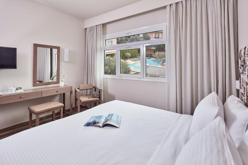 アテネにあるCivitel Espritのベッド、デスク、窓が備わるホテルルームです。